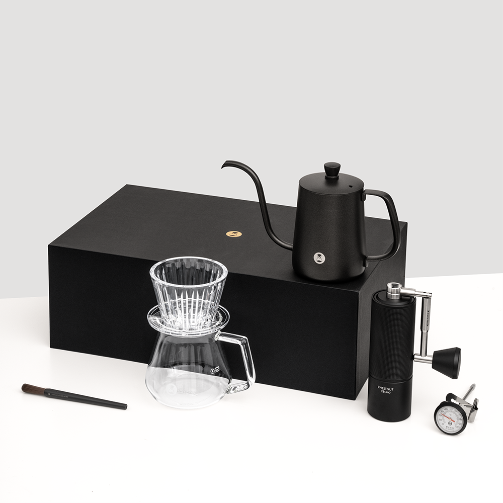 TIMEMORE C3S Pro pour-over coffee kit with black grinder, transparent B75 dripper, glass server, gooseneck kettle, cleaning brush, and thermometer on black box