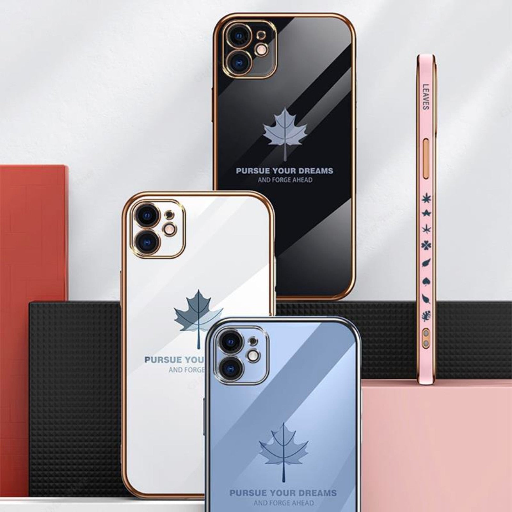 Three iPhone 14 Anacotte cases with maple leaf design and "Pursue Your Dreams" text in black, white, and blue.